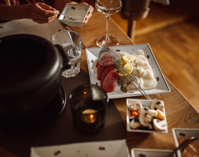 Ein gedeckter Tisch mit frischem Fisch, Gemüse, Cocktails und Fondue