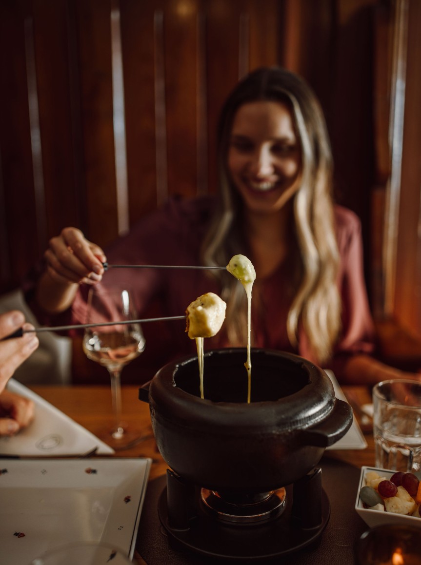 Eine Frau genießt ein Käsefondue im Fonduerestaurant Ennshof in Flachau
